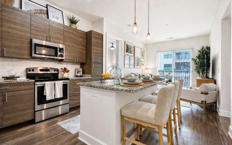  Open-concept kitchen with granite island, bar seating, and stainless steel appliances leading into a bright living area.