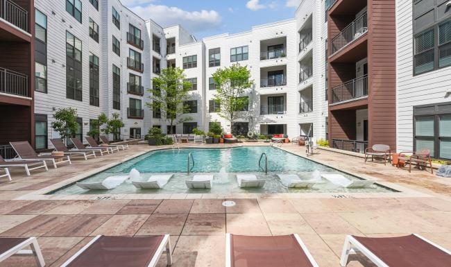 a swimming pool in a courtyard between buildings with lounge chairs