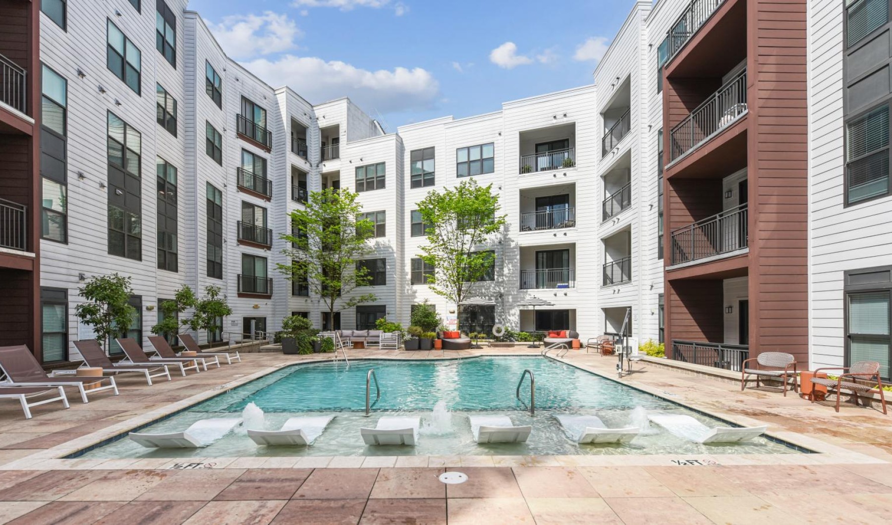 a swimming pool in a courtyard between buildings with lounge chairs